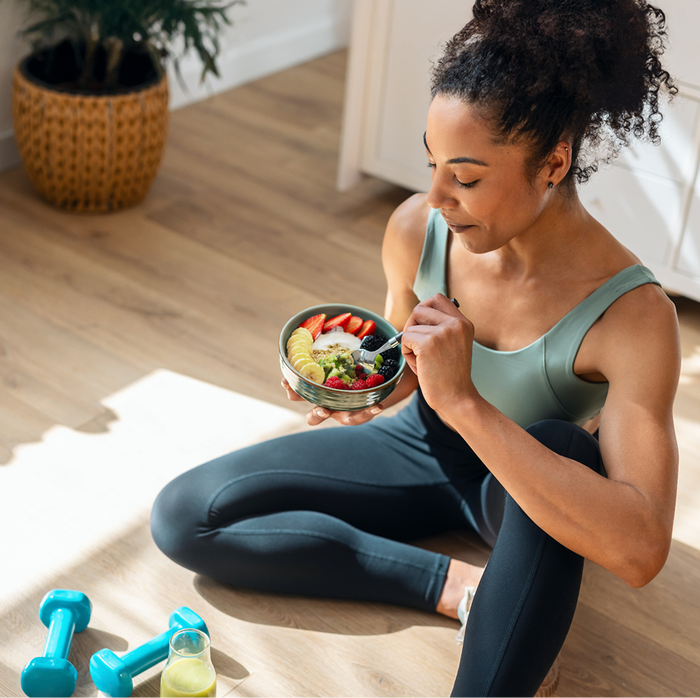 woman in athletic wear eating a granola bowl